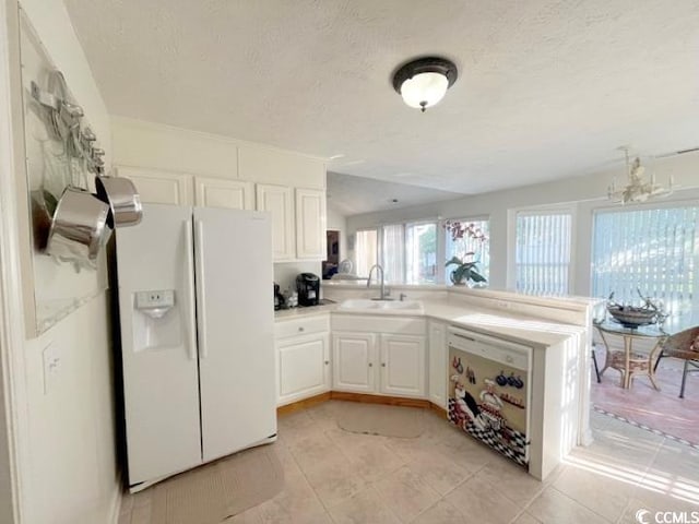 kitchen with kitchen peninsula, white cabinetry, a notable chandelier, sink, and white refrigerator with ice dispenser