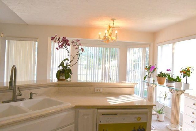 kitchen featuring white dishwasher, sink, white cabinets, and a textured ceiling