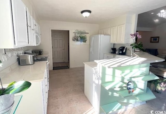 kitchen featuring white cabinetry, sink, kitchen peninsula, and white appliances