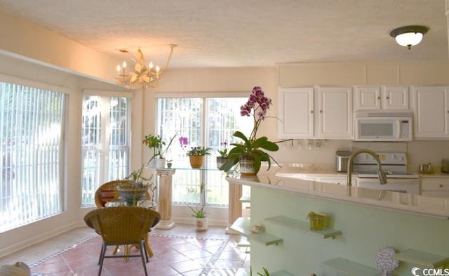 kitchen featuring white appliances, light tile patterned floors, white cabinetry, and a wealth of natural light