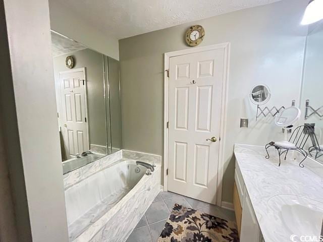 bathroom featuring vanity, a textured ceiling, tile patterned floors, and a bathtub