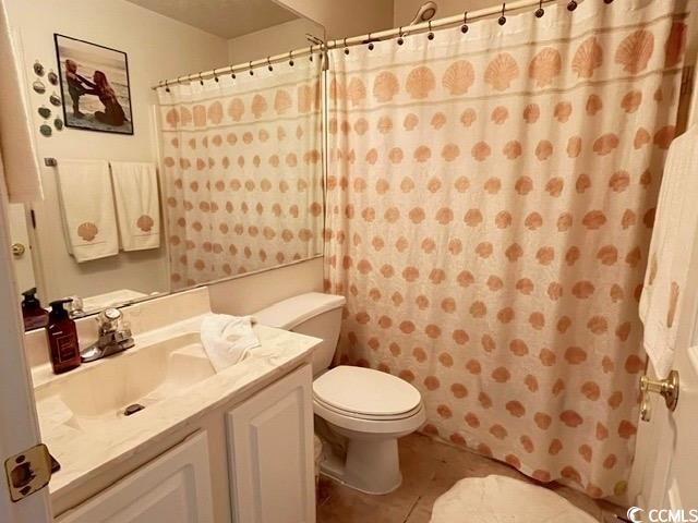 bathroom featuring vanity, tile patterned flooring, toilet, and walk in shower