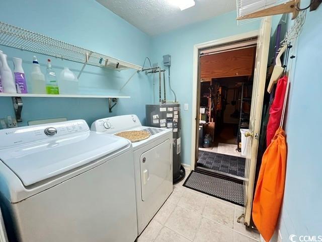 clothes washing area with electric water heater, separate washer and dryer, and light tile patterned floors