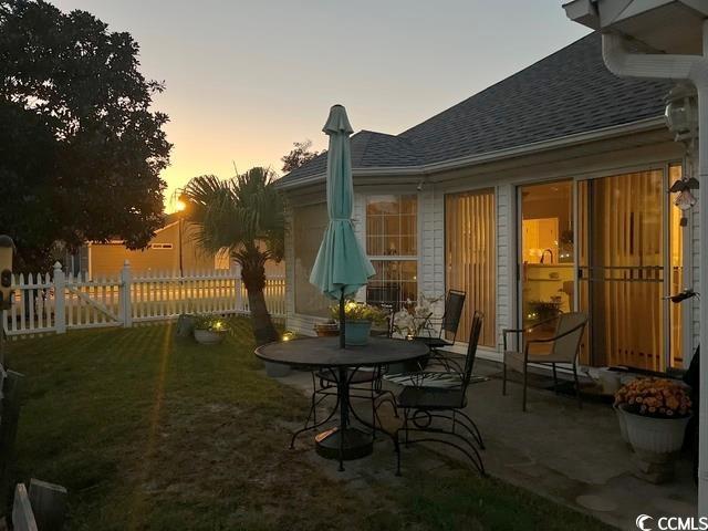 patio terrace at dusk featuring a lawn