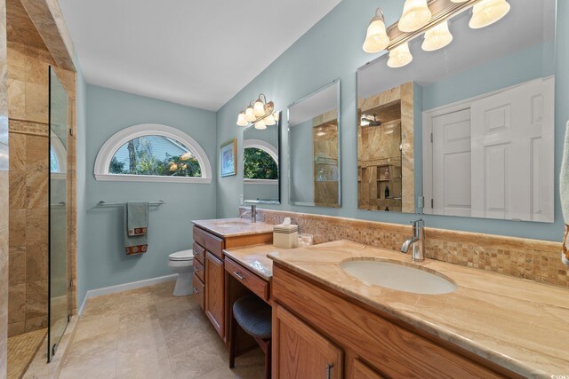 bathroom with vanity, tiled shower, and toilet