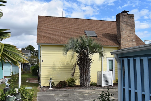 exterior space with a chimney and a shingled roof