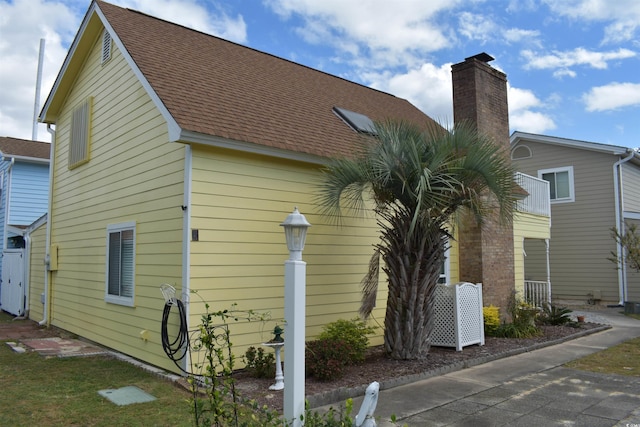 view of property exterior featuring a shingled roof and a chimney