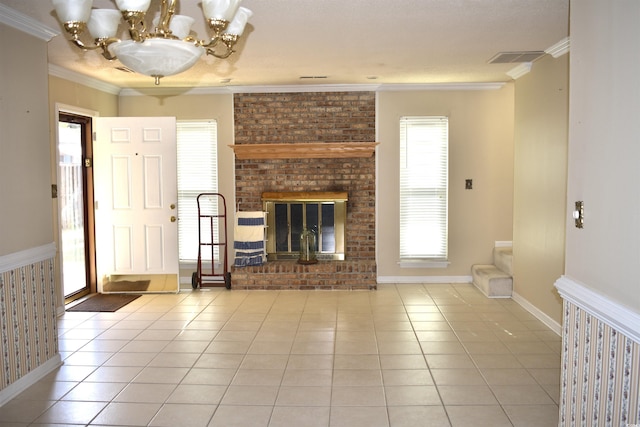 unfurnished living room featuring ornamental molding, visible vents, a chandelier, a brick fireplace, and tile patterned floors