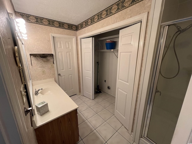 bathroom with a textured ceiling, vanity, a stall shower, and tile patterned floors
