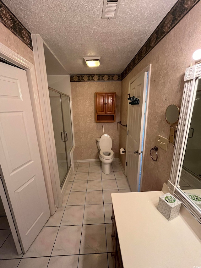 bathroom featuring tile patterned floors, toilet, vanity, a textured ceiling, and walk in shower