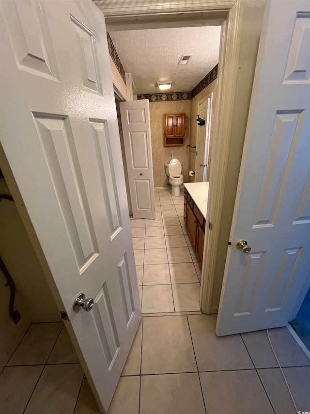 bathroom with vanity, toilet, tile patterned floors, and a textured ceiling