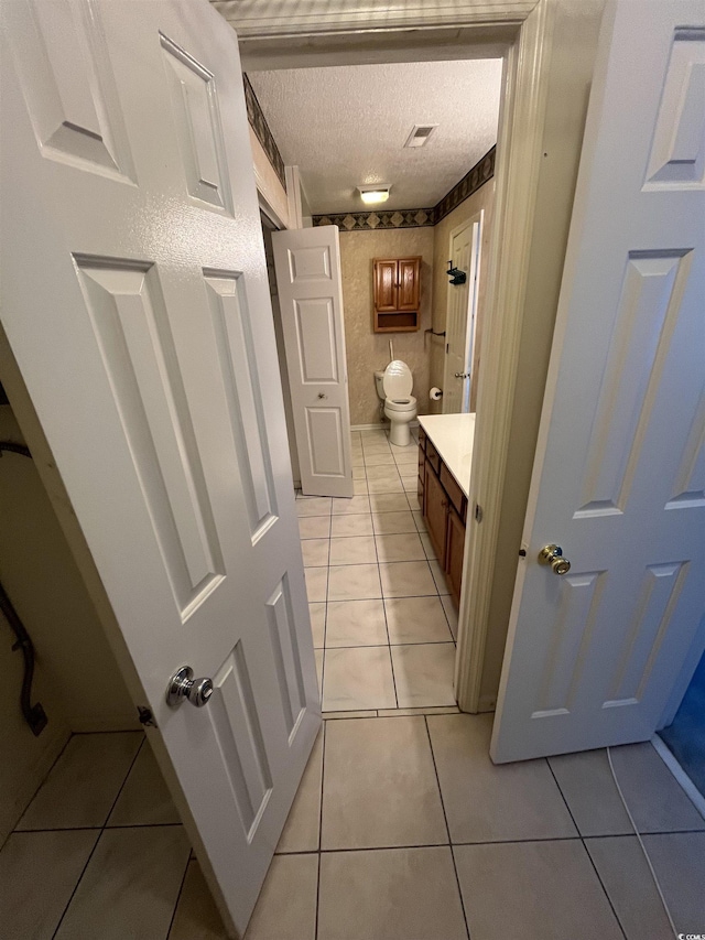 bathroom with tile patterned floors, visible vents, a textured ceiling, and toilet