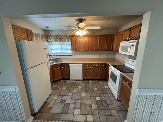 kitchen featuring brown cabinetry, white appliances, a sink, and ceiling fan