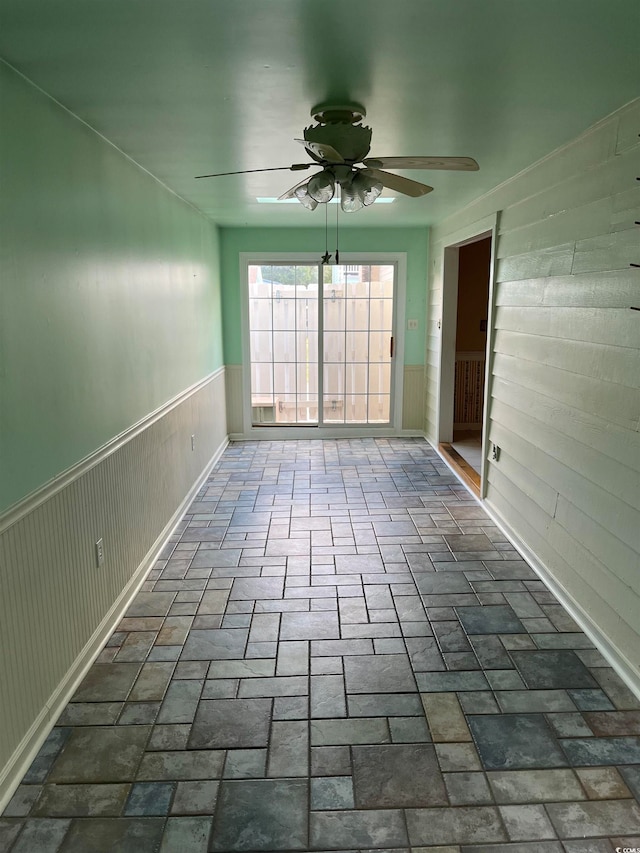 empty room with ceiling fan and wooden walls