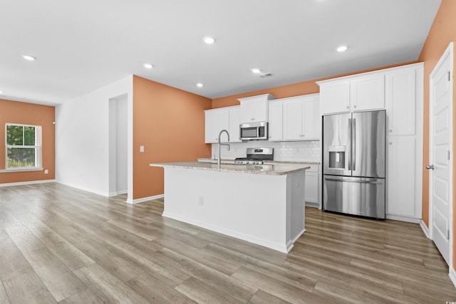 kitchen with appliances with stainless steel finishes, white cabinetry, and a kitchen island with sink