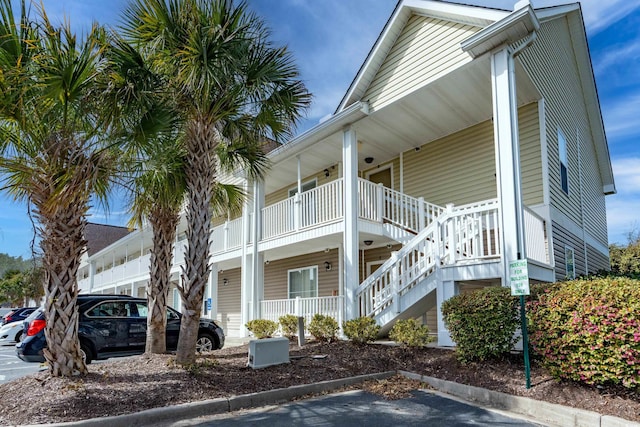 view of property with uncovered parking and stairway