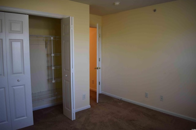 unfurnished bedroom with a closet and dark colored carpet