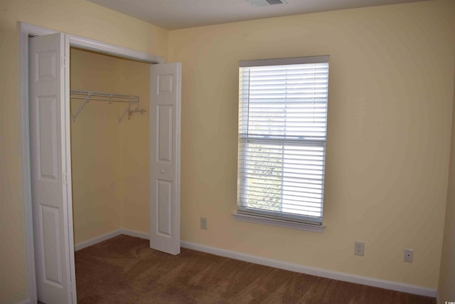 unfurnished bedroom featuring a closet and dark colored carpet