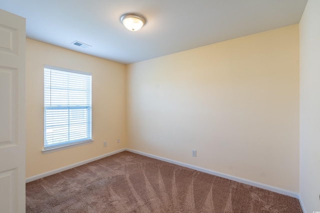 unfurnished room featuring carpet flooring, visible vents, and baseboards