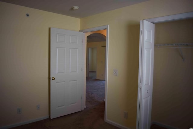 unfurnished bedroom featuring dark colored carpet and a closet