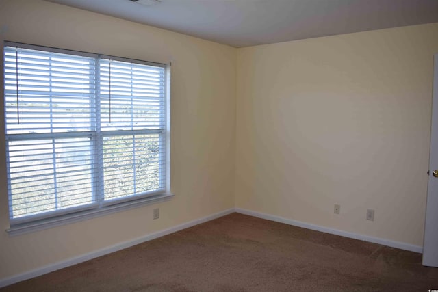 unfurnished room with plenty of natural light and dark carpet