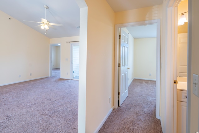 corridor with lofted ceiling, baseboards, and carpet flooring