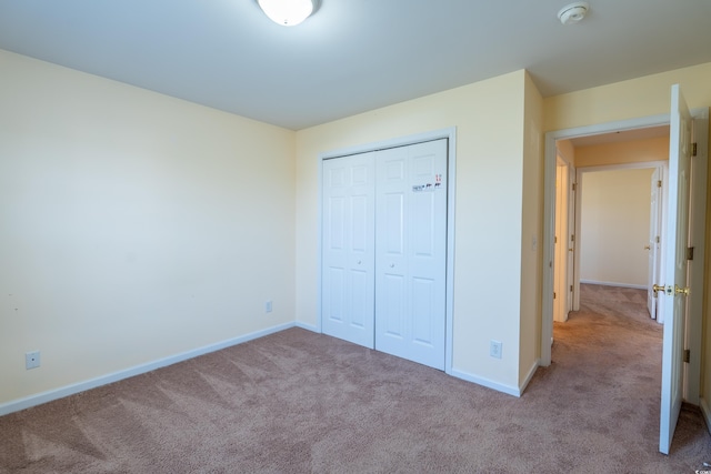 unfurnished bedroom with carpet, a closet, and baseboards