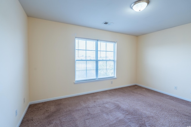 spare room featuring carpet, visible vents, and baseboards