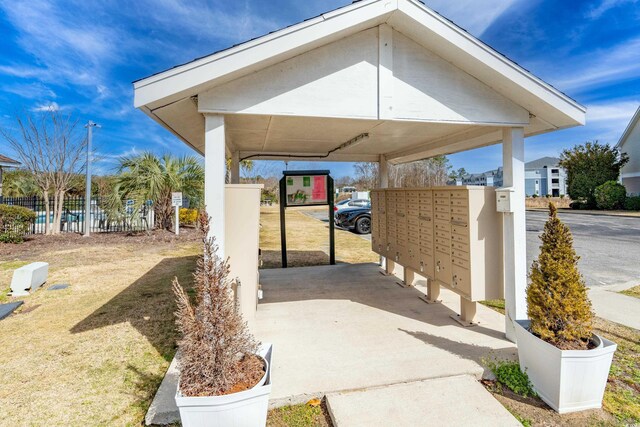 view of patio featuring a carport, fence, and mail area