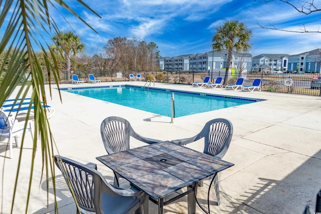 community pool featuring a residential view, fence, and a patio