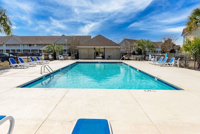 pool with a patio area, a residential view, and fence