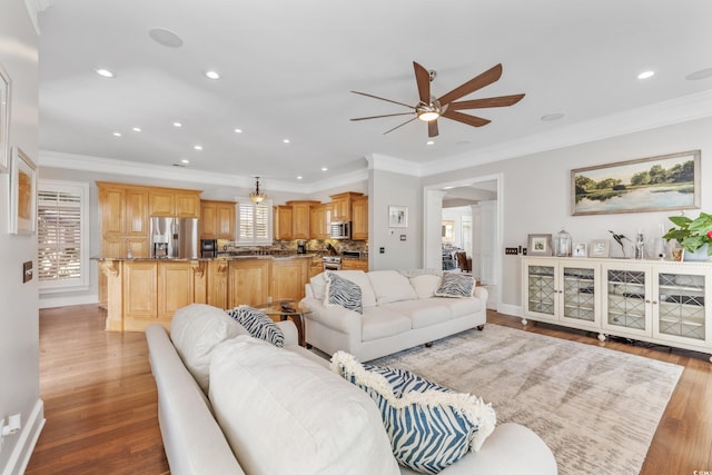 living room featuring ornamental molding, light wood-type flooring, and ceiling fan