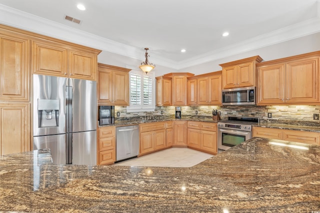 kitchen featuring crown molding, appliances with stainless steel finishes, decorative light fixtures, and dark stone counters