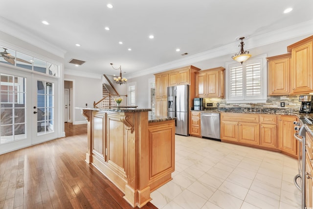 kitchen with backsplash, ornamental molding, a center island, decorative light fixtures, and appliances with stainless steel finishes