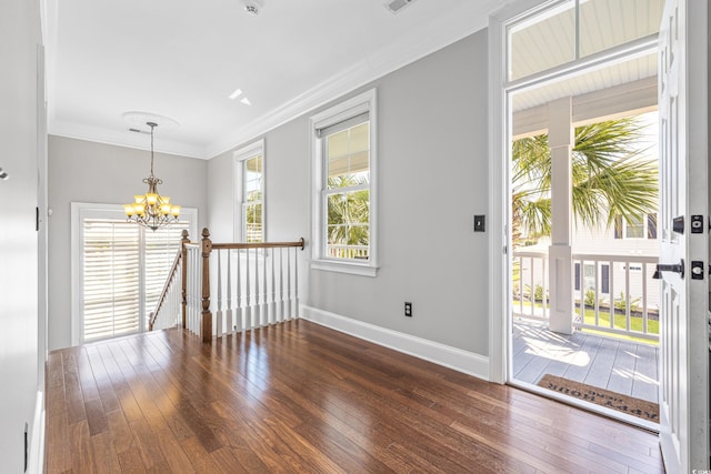 entrance foyer with ornamental molding, an inviting chandelier, and dark hardwood / wood-style floors