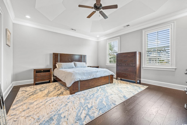 bedroom with crown molding, dark hardwood / wood-style floors, a tray ceiling, and ceiling fan