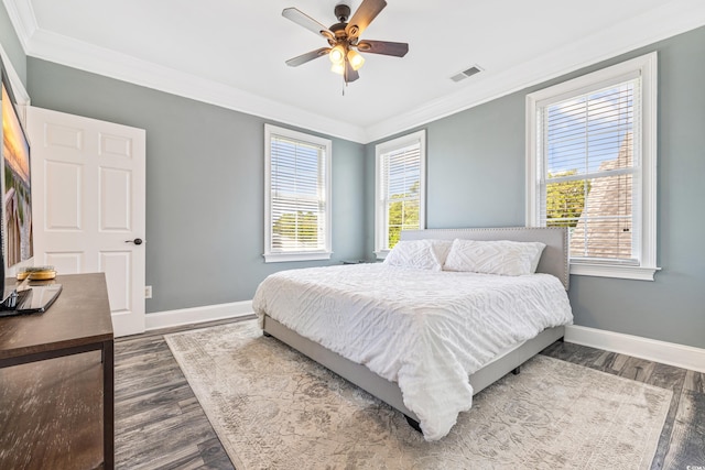 bedroom with multiple windows, dark wood-type flooring, crown molding, and ceiling fan