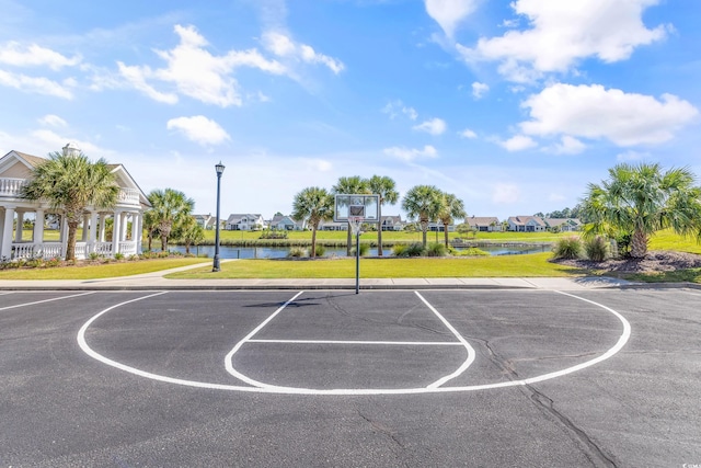 view of basketball court featuring a yard and a water view