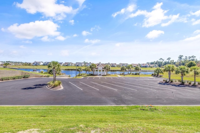 view of vehicle parking featuring a lawn and a water view