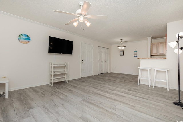 unfurnished living room featuring crown molding, ceiling fan, light hardwood / wood-style floors, and a textured ceiling