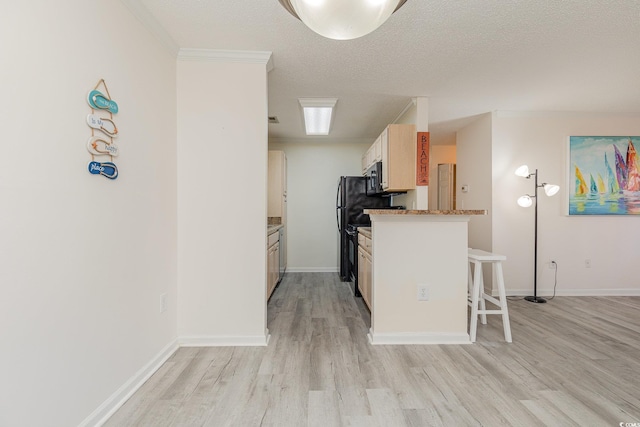 kitchen featuring ornamental molding, a breakfast bar, a textured ceiling, black appliances, and light hardwood / wood-style floors