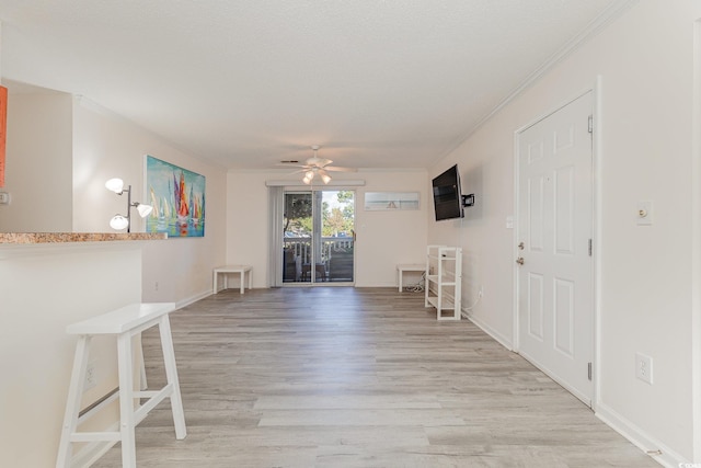 unfurnished living room with ceiling fan, light hardwood / wood-style floors, and ornamental molding