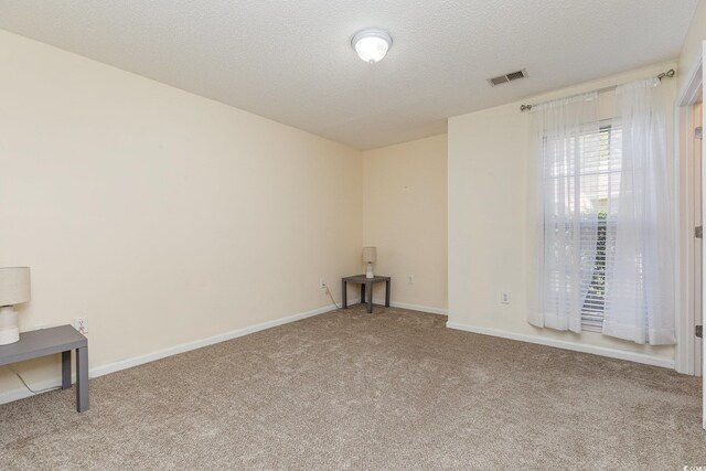 unfurnished room featuring light colored carpet and a textured ceiling