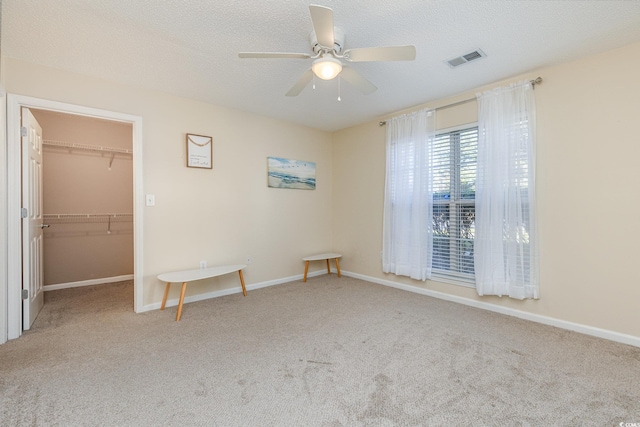 unfurnished bedroom with ceiling fan, a closet, light colored carpet, and a spacious closet