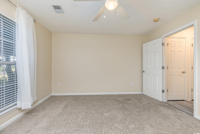 empty room with light carpet, a textured ceiling, and ceiling fan