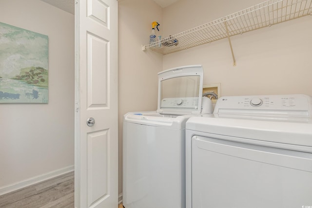 washroom with washer and clothes dryer and light hardwood / wood-style flooring