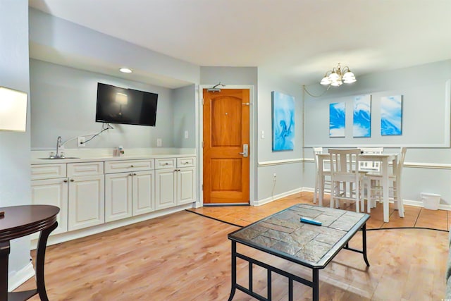 living room featuring light hardwood / wood-style flooring, a notable chandelier, and sink