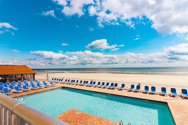 view of pool featuring a water view and a beach view