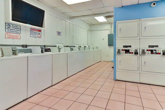 laundry area featuring electric panel, light tile patterned flooring, independent washer and dryer, and stacked washing maching and dryer