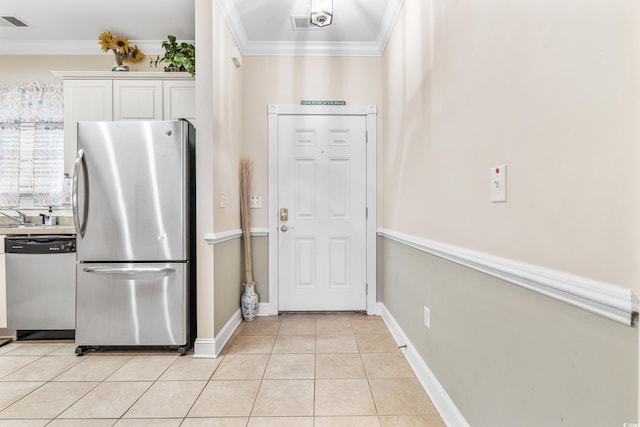 kitchen featuring white cabinetry, light tile patterned flooring, appliances with stainless steel finishes, and ornamental molding